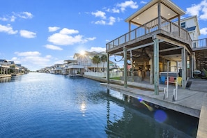 A waterfront property with a covered deck, a pool, and a view of the water.