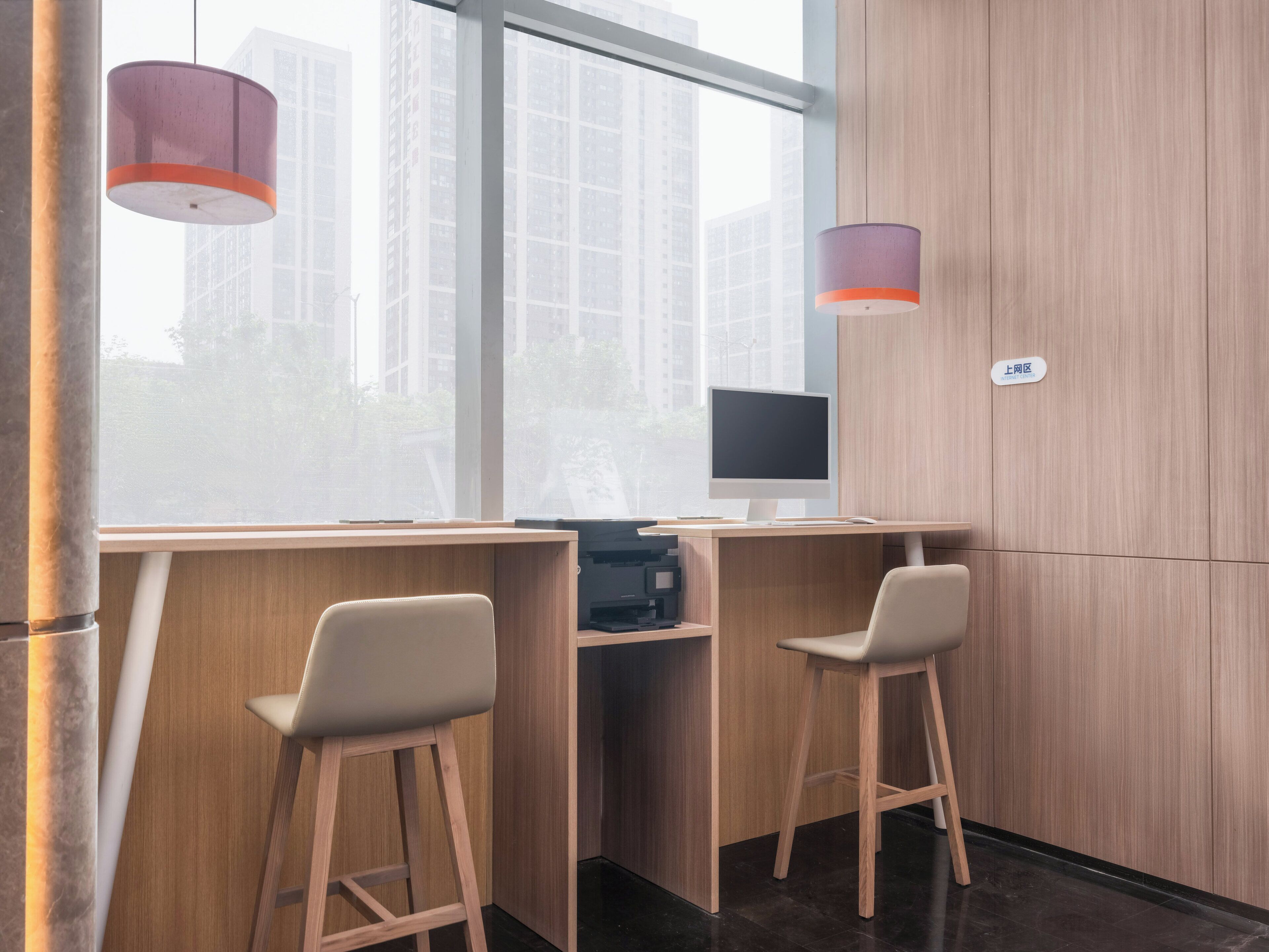 Un espacio de oficina moderno con dos escritorios de madera, un monitor de computadora y dos sillas.
