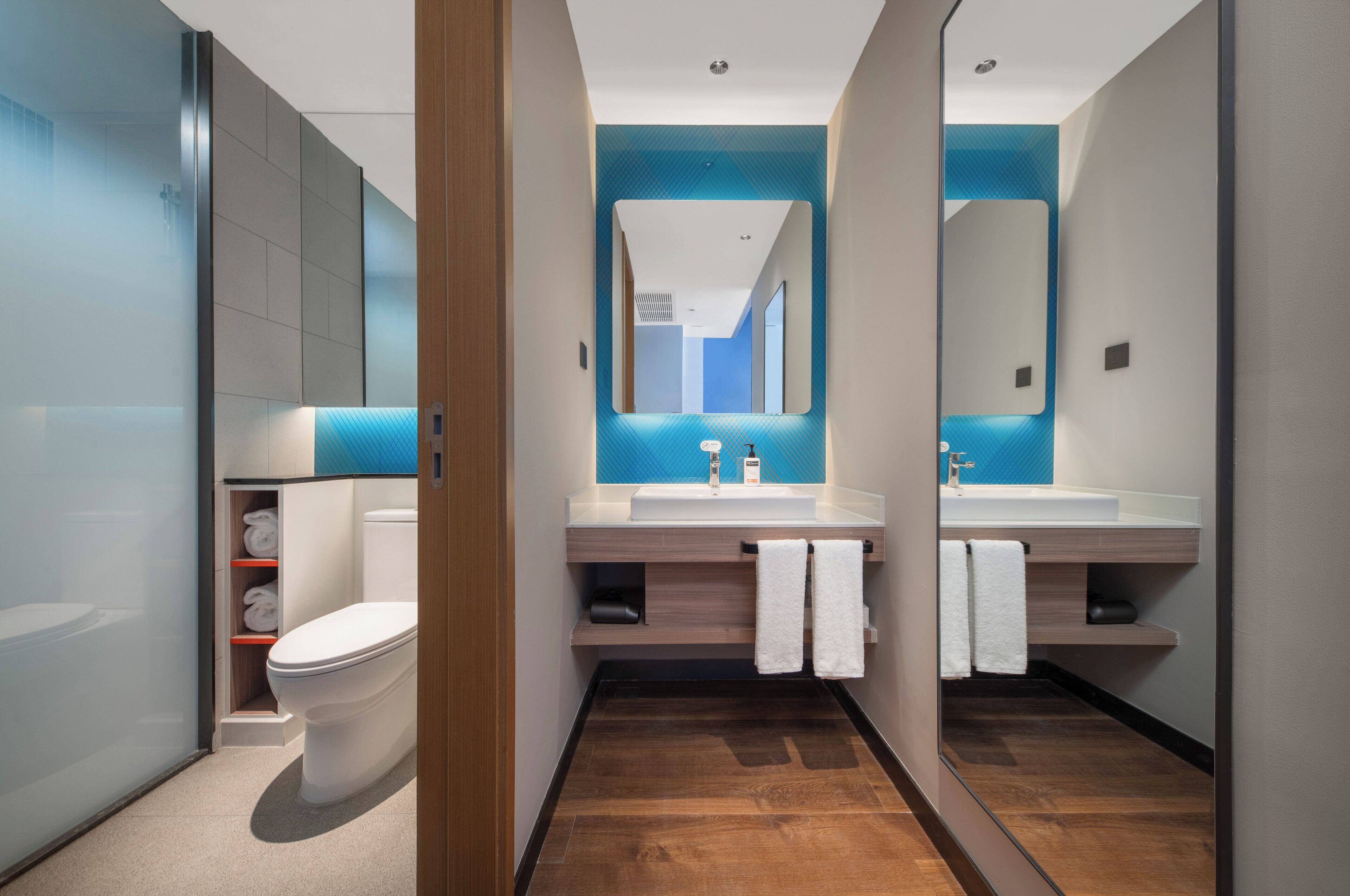 A modern bathroom with a toilet, two sinks, and a mirror.