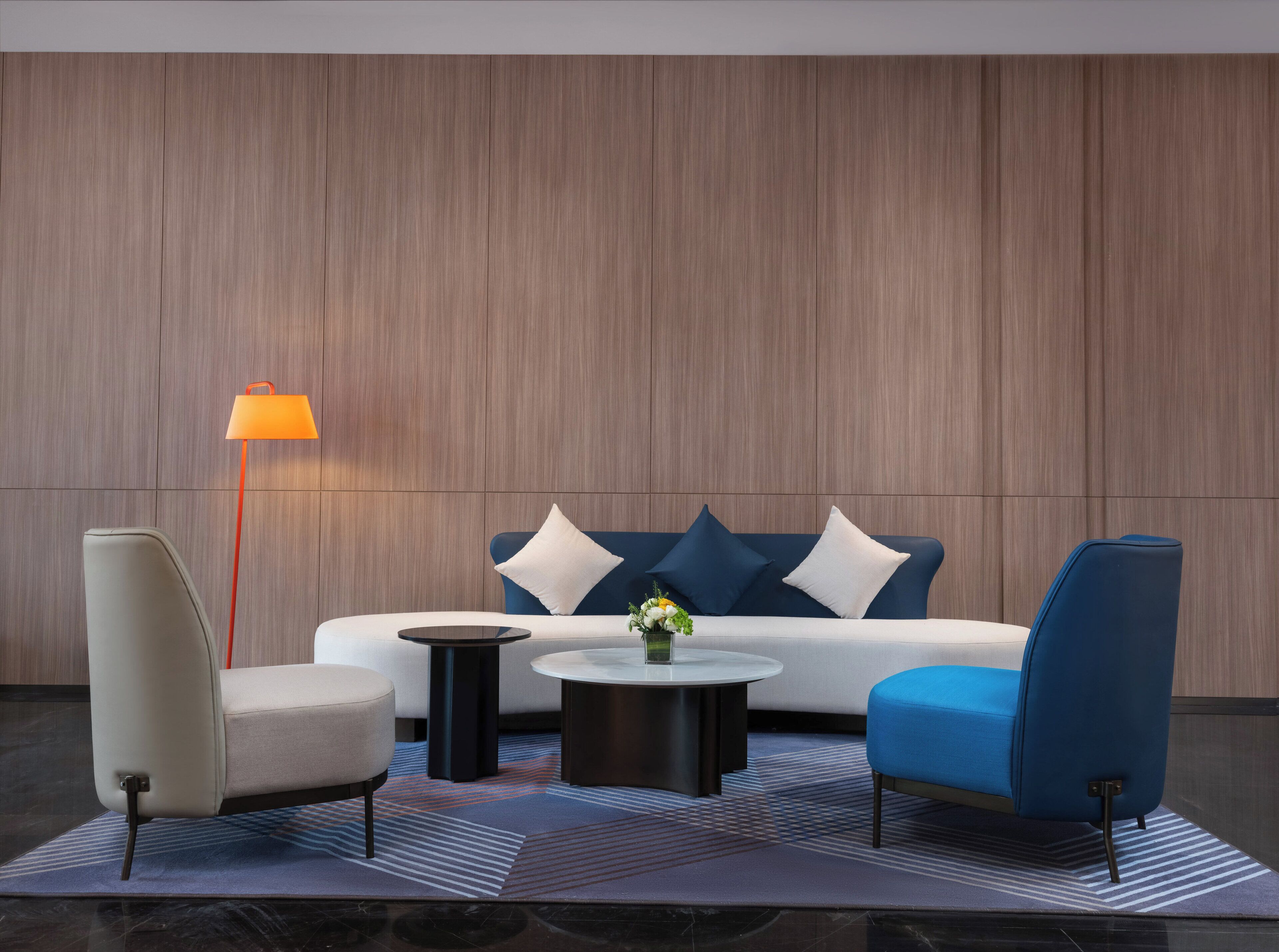 A modern lounge area with a sofa, two armchairs, a coffee table, and a floor lamp.