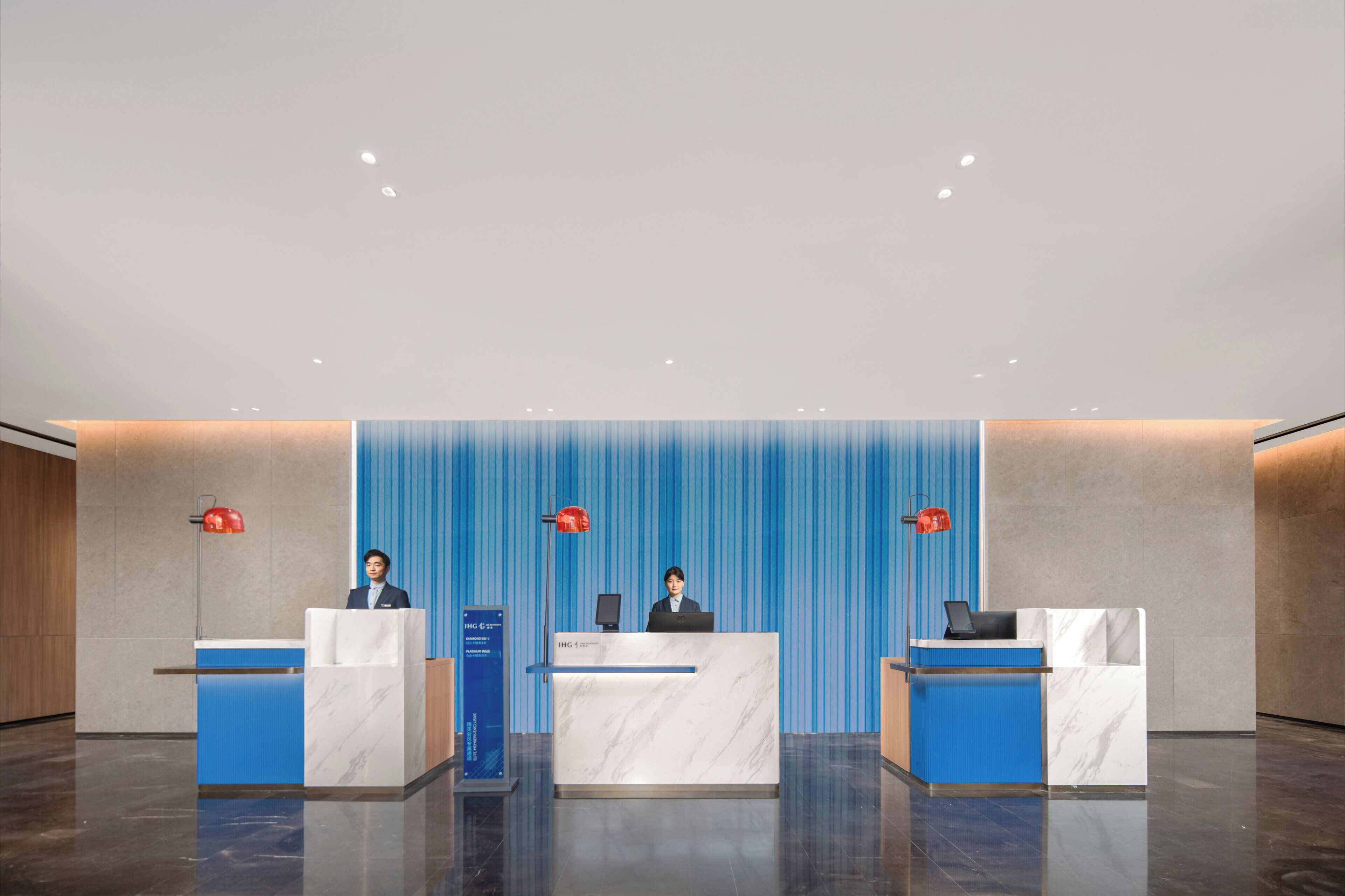 A hotel reception area with three reception desks, each with a computer and a red lamp.