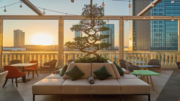 A rooftop lounge with a sofa, chairs, and a potted tree. - Holiday Inn Tashkent City by IHG (Tashkent)