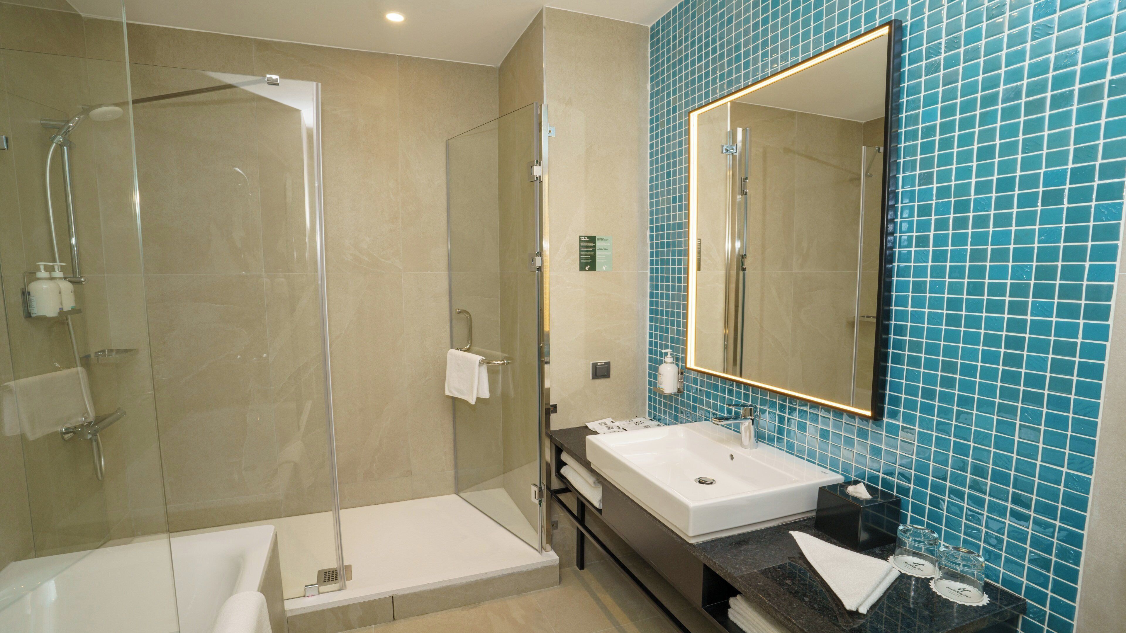 Une salle de bain moderne dotée d’une douche à parois de verre, d’une baignoire et d’un meuble-lavabo avec un évier et un miroir.