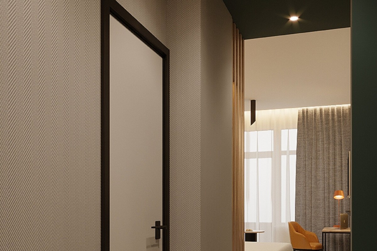 A hotel room with a large bed, a desk with a lamp, a chair, and a window with curtains.