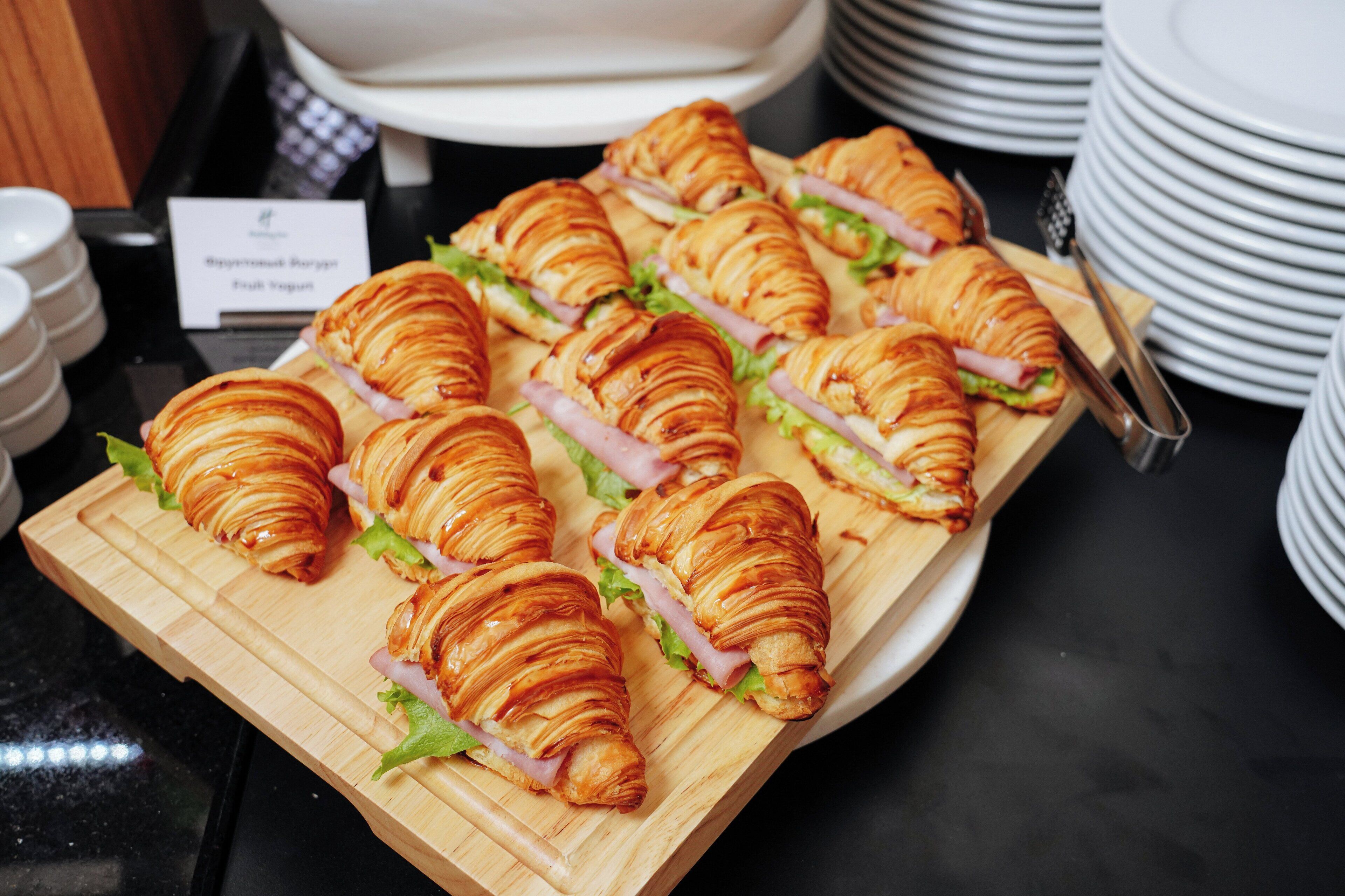 Una bandeja de croissants con jamón y queso sobre una tabla de madera.