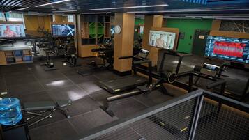Une salle de sport équipée de divers appareils d’exercice, notamment des tapis de course, des appareils de musculation et un vélo d’appartement.