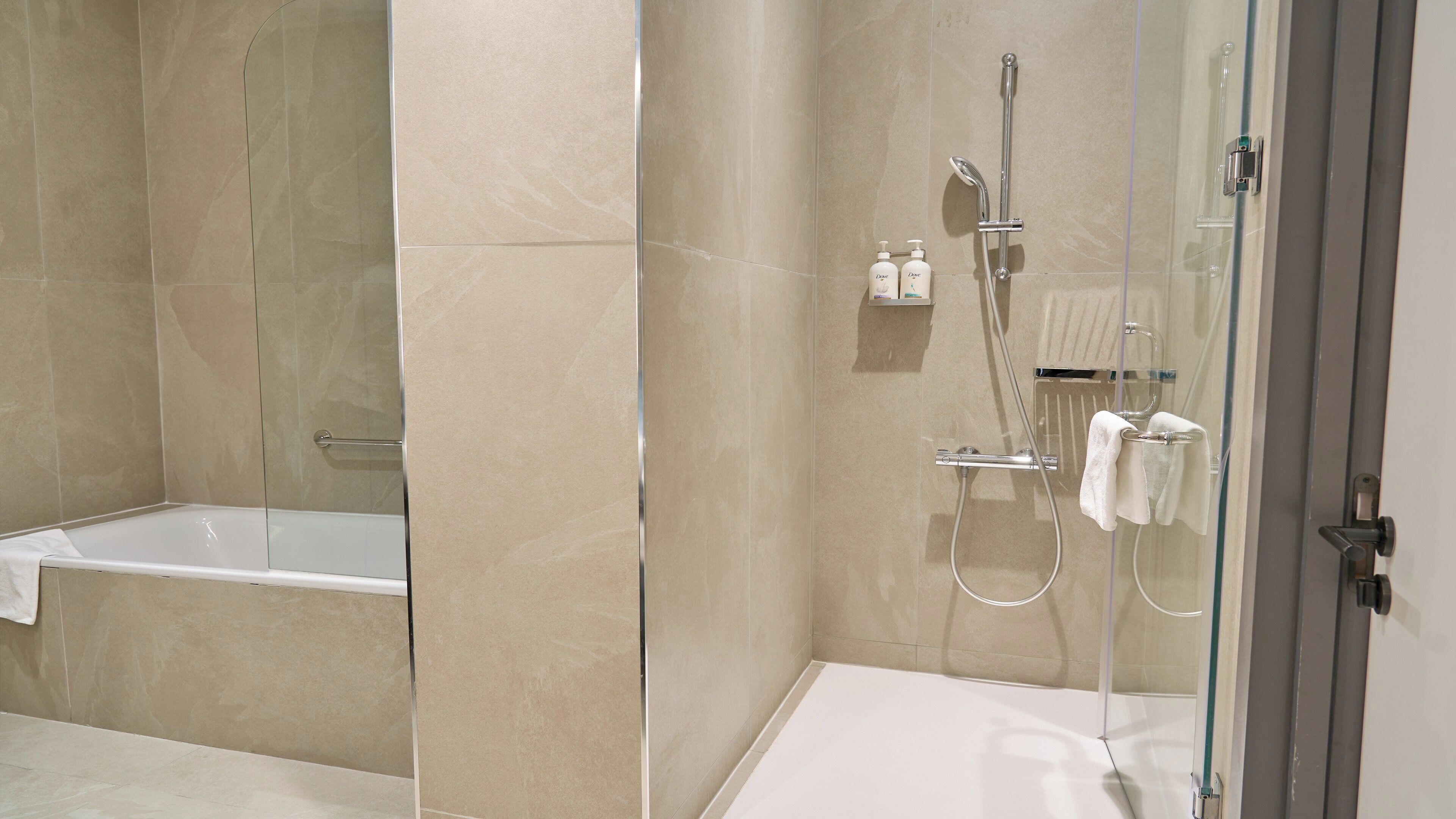 A modern bathroom with a glass-enclosed shower, a separate bathtub, and a glass-enclosed toilet.