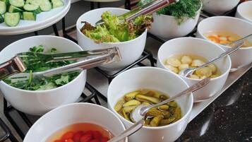 A buffet table with various food items including salads, vegetables, and soups.