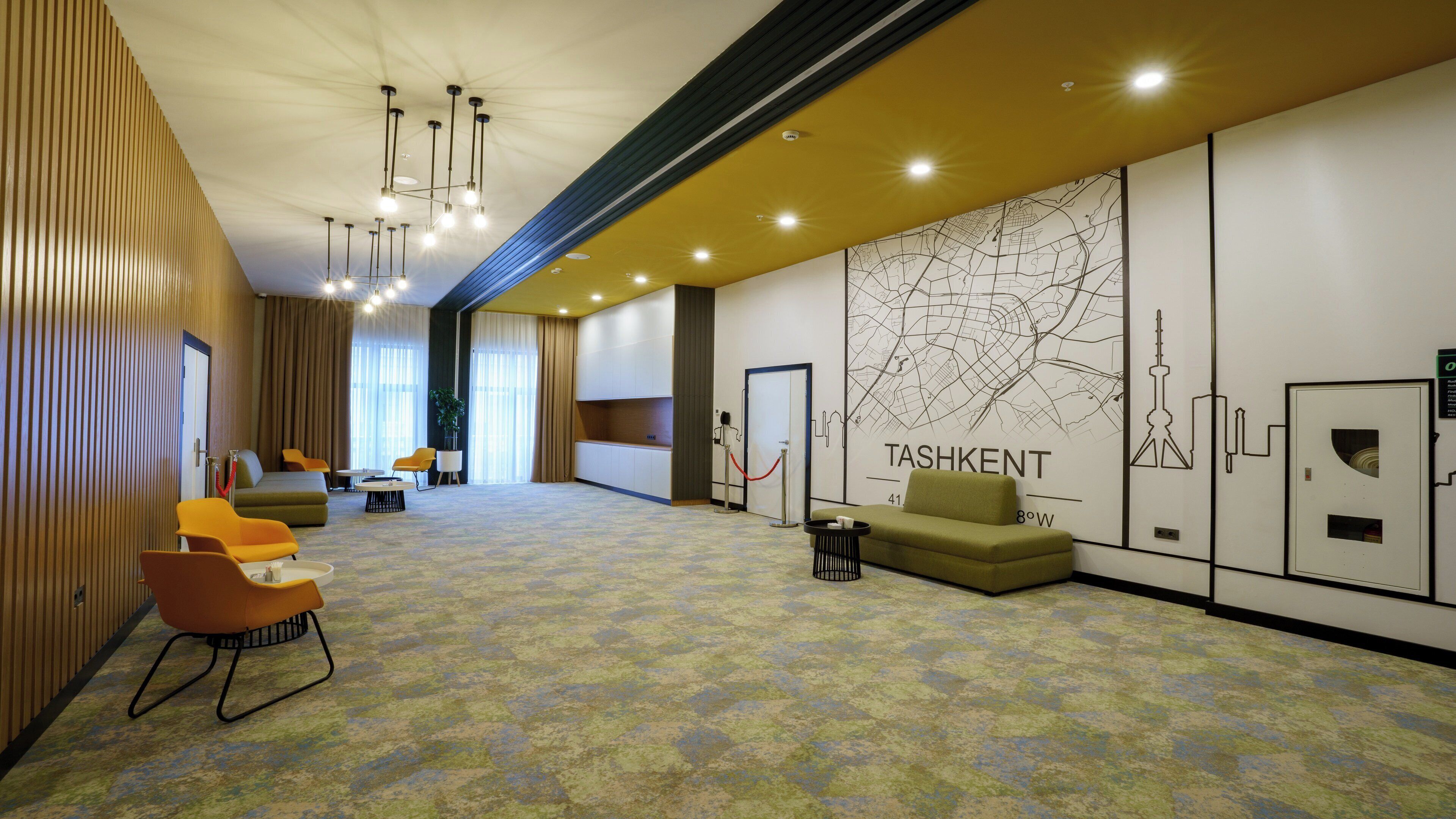 A hotel lobby with a reception desk, seating area, and a large wall map.