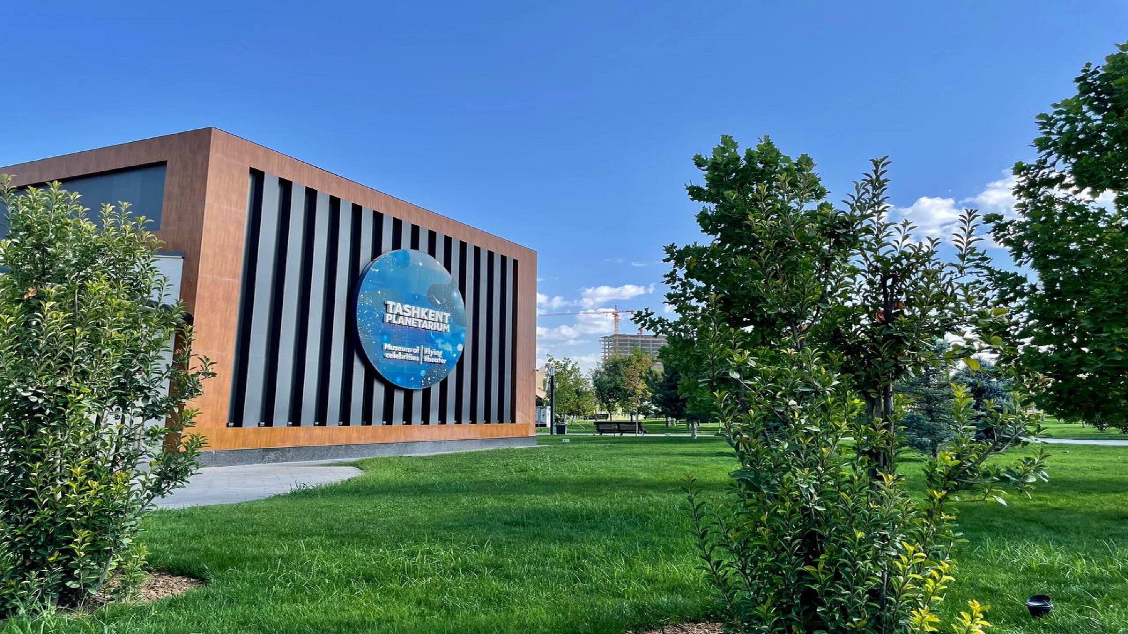 A modern building with a large sign for the Tashkent Planetarium.