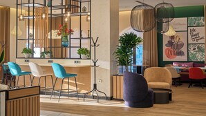 A modern interior with a seating area featuring blue and white chairs, a black floor lamp, and a large potted plant. - Holiday Inn Tashkent City by IHG (Tashkent)