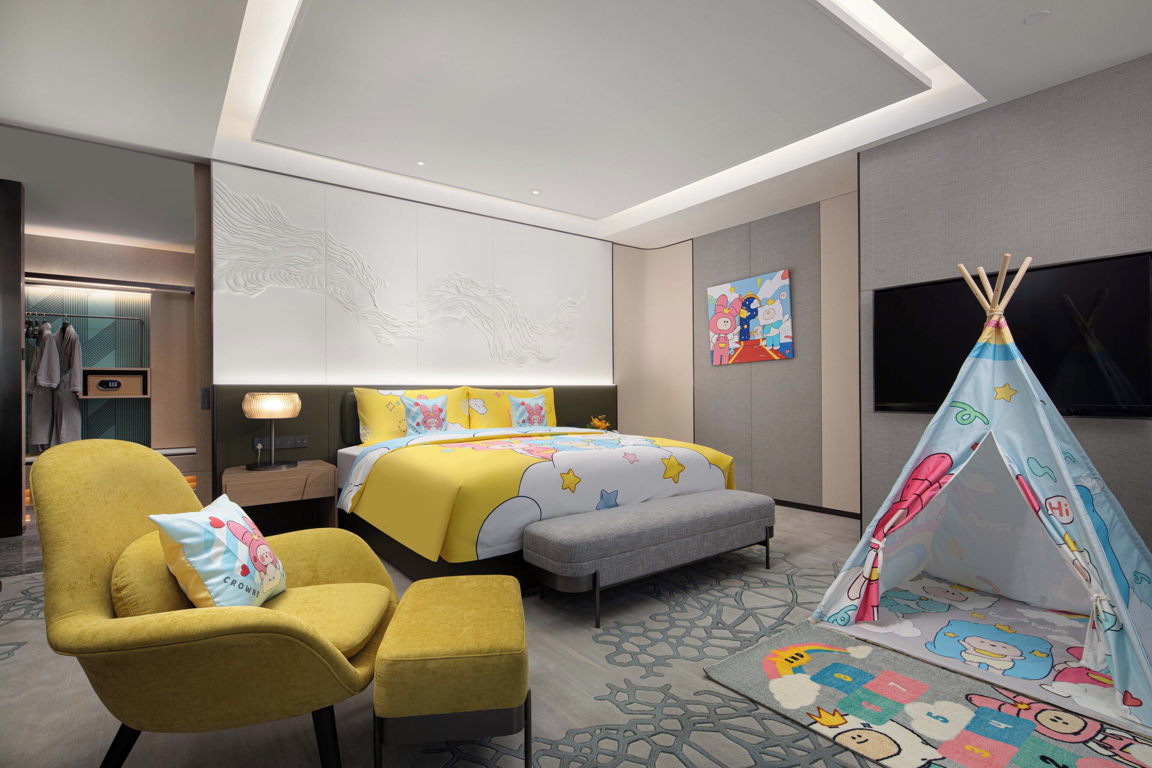 A hotel room with a bed, a yellow armchair, a grey bench, a tent, and a television.