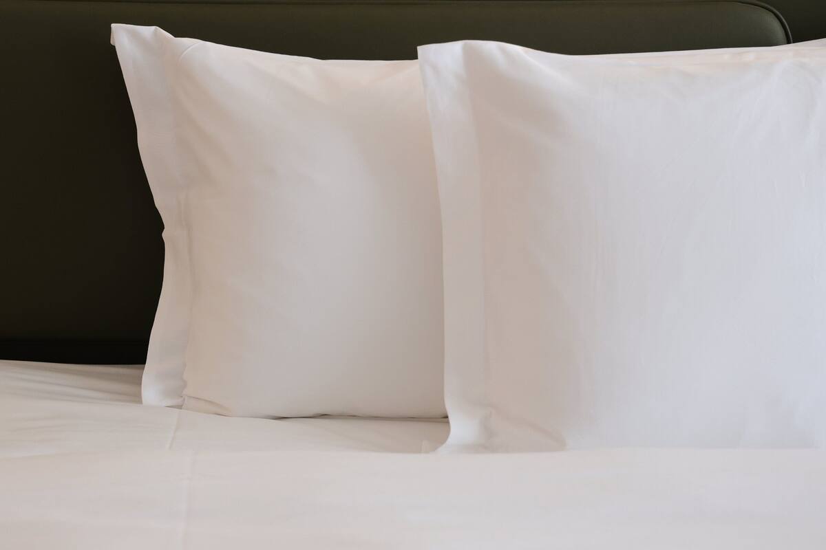 A bed with white bedding and two white pillows.