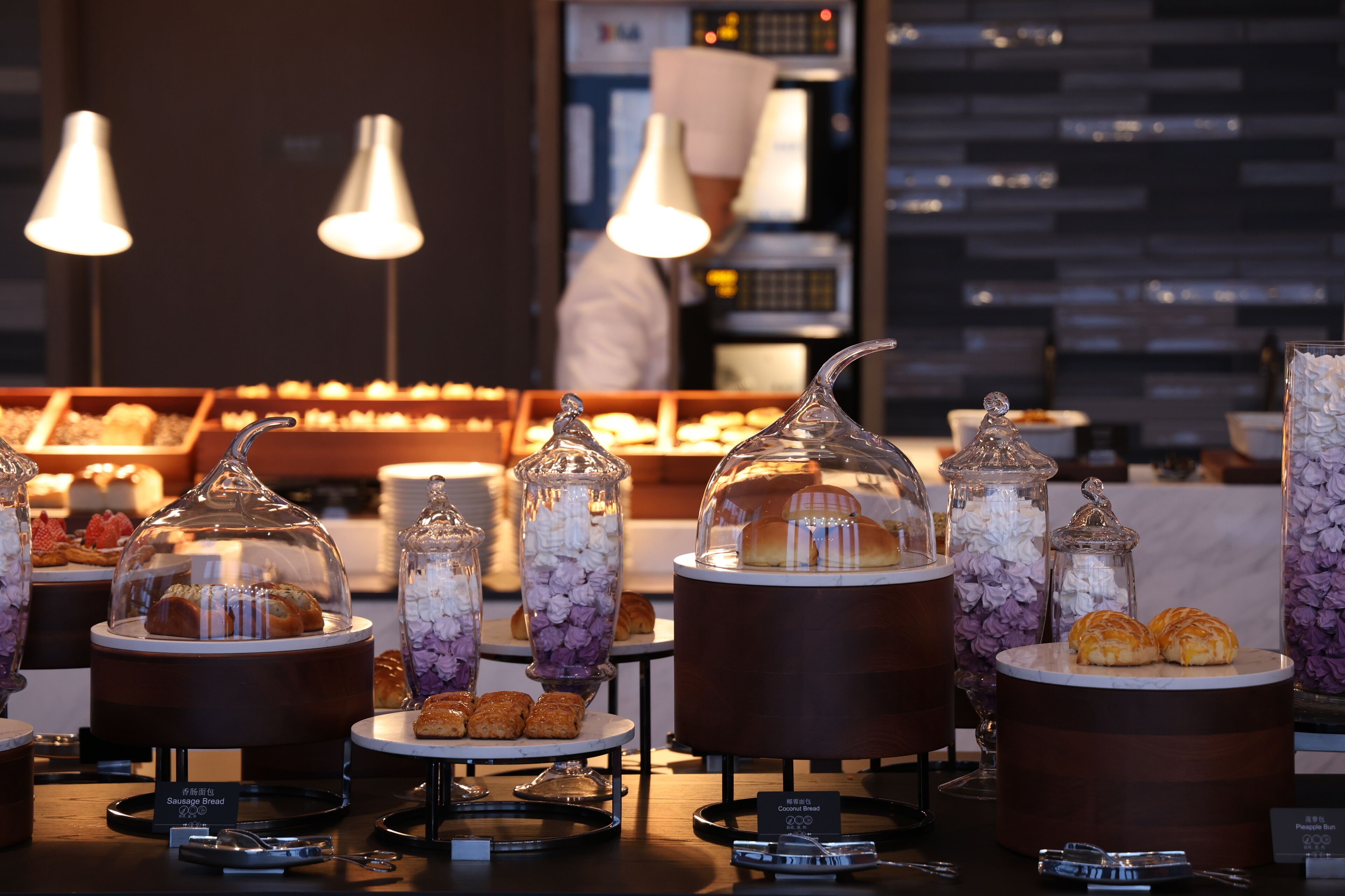 A buffet with various food items, including pastries and desserts, displayed in glass containers and under glass domes.