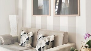 A neutral-toned sofa with geometric-patterned cushions, a white towel, and two framed pictures on the wall.