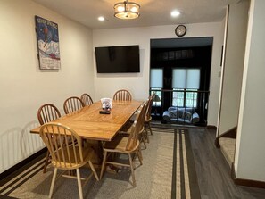 Un salón de conferencias con una mesa de madera, seis sillas, un televisor de pantalla plana y un cartel en la pared.