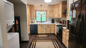 Una cocina compacta con armarios de madera, horno empotrado, refrigerador y lavadora.
