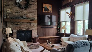 Una sala de estar acogedora con chimenea de ladrillo, televisor de pantalla plana y asientos cómodos.