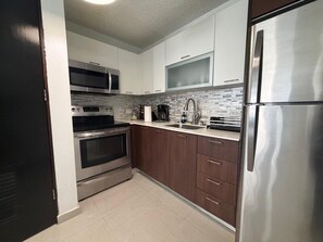 A modern kitchen with stainless steel appliances, a microwave, oven, and a refrigerator. - Bright, Comfy Apt @ Miramar (San Juan)