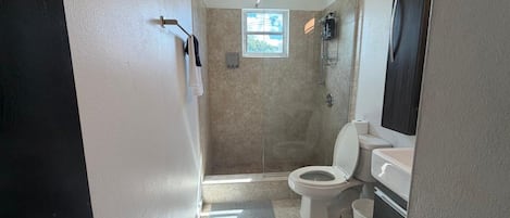 A bathroom with a shower, toilet, and sink.