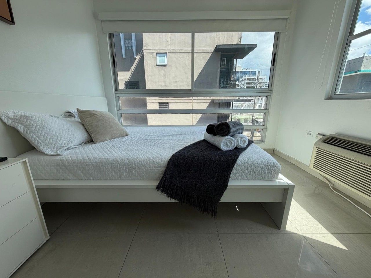 Un dormitorio moderno con cama, ventana y radiador.