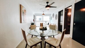 A dining area with a glass table, four chairs, a ceiling fan, and a view of the outdoors. - Bright, Comfy Apt @ Miramar (San Juan)