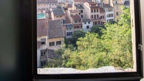 Une vue par la fenêtre sur un paysage urbain, avec des immeubles et le clocher d’une église.