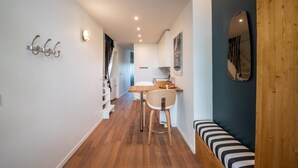 Une cuisine moderne avec une table en bois, des tabourets de bar, un banc et un miroir au mur.