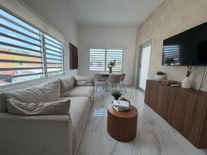 A modern living room with a sectional sofa, a wooden coffee table, and a TV mounted on the wall.