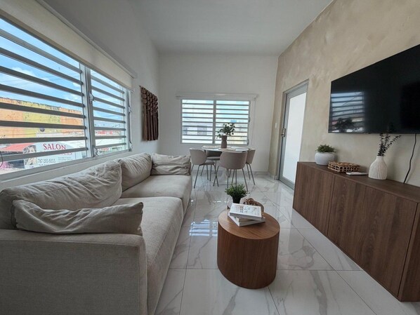 A modern living room with a sectional sofa, a wooden coffee table, and a TV mounted on the wall.