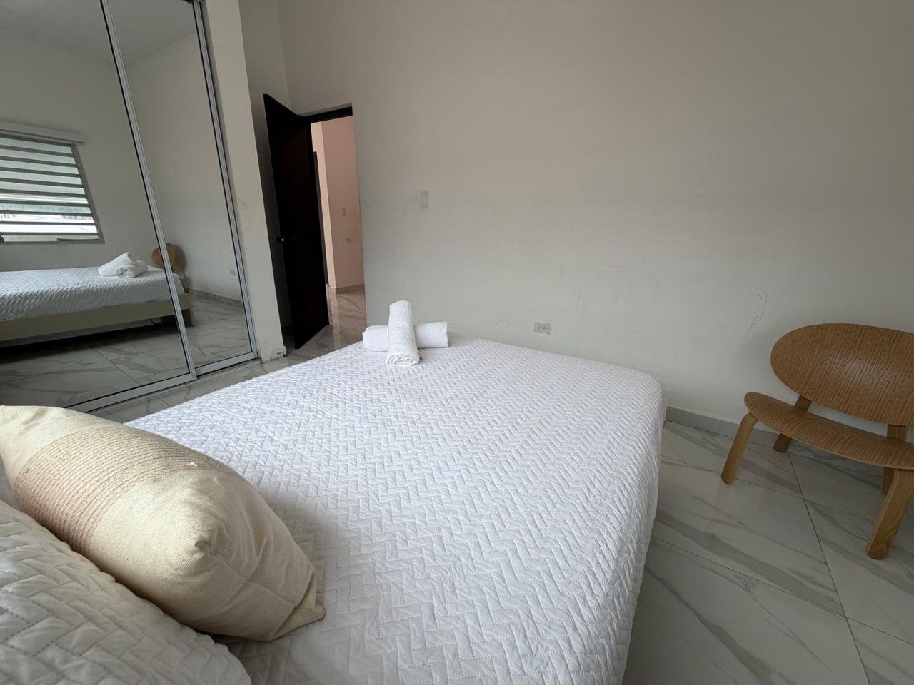 Une chambre à coucher avec un lit, une chaise et un miroir.