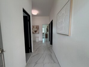 Un pasillo con piso de mármol, una obra de arte enmarcada en la pared y una puerta que da a otra habitación.
