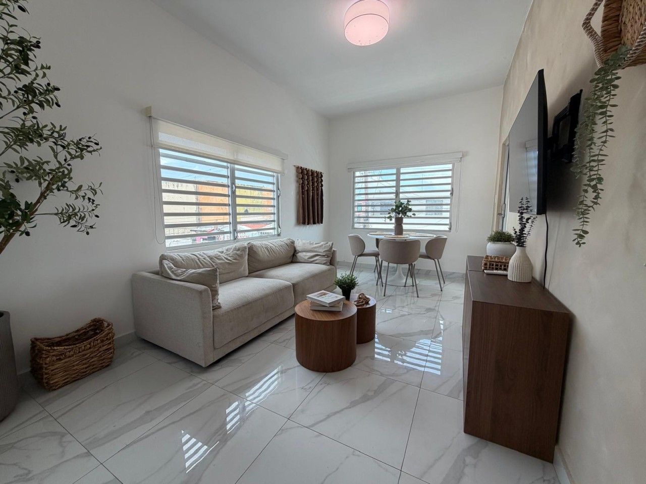 A modern living room with a sofa, coffee table, and a TV mounted on the wall.