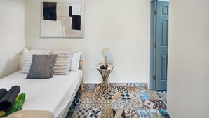 Une chambre à coucher avec un lit, une table de chevet avec une lampe, un climatiseur fixé au mur et un sol à motifs.