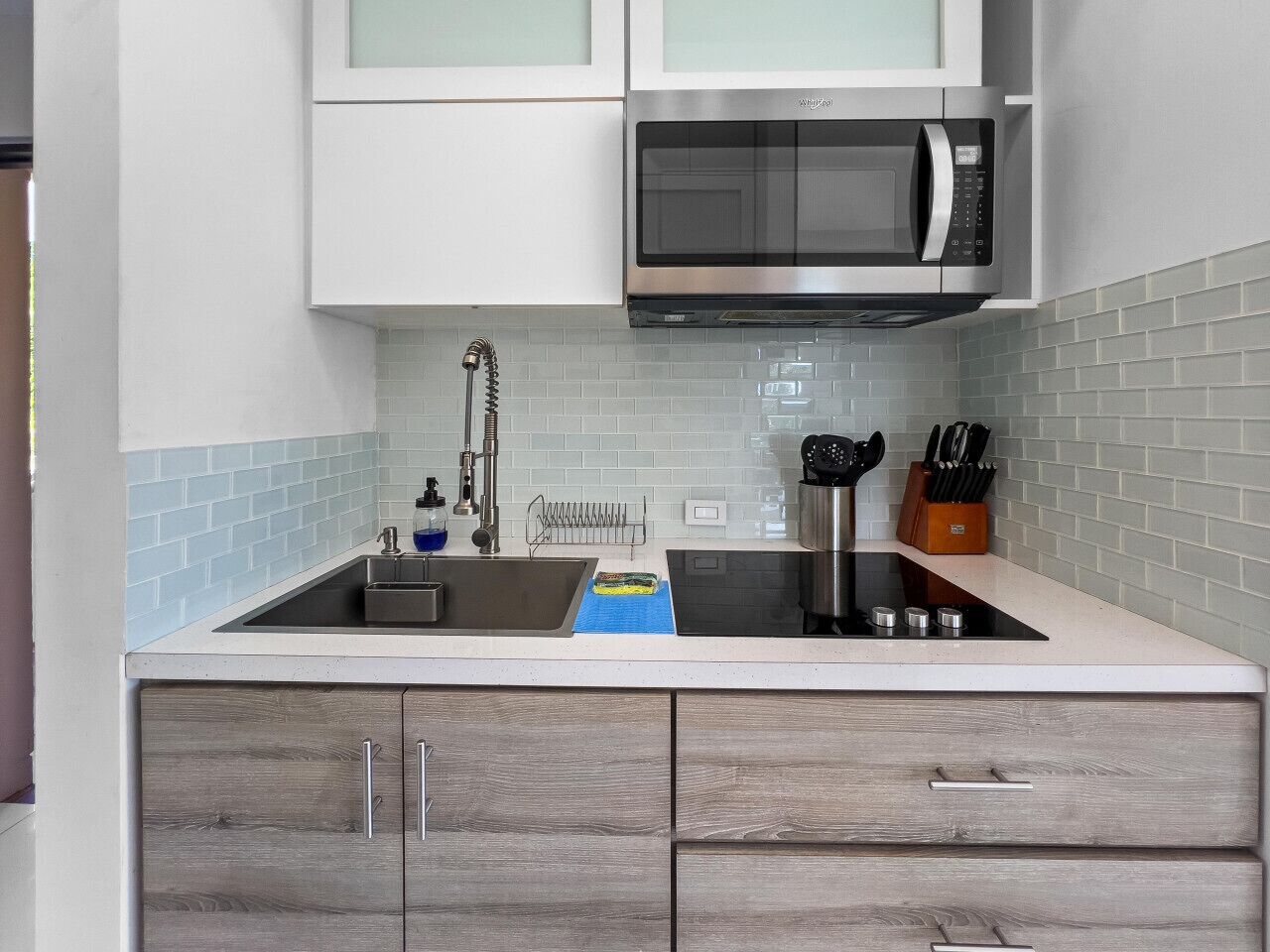 Una cocina con un lavamanos de acero inoxidable, un microondas y armarios de madera.