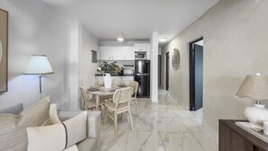 A modern living room with a sofa and a dining area with a table and chairs.