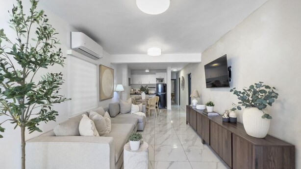 A modern living room with a sofa, a coffee table, and a TV mounted on the wall.