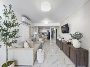 A modern living room with a sofa, a coffee table, and a TV mounted on the wall.