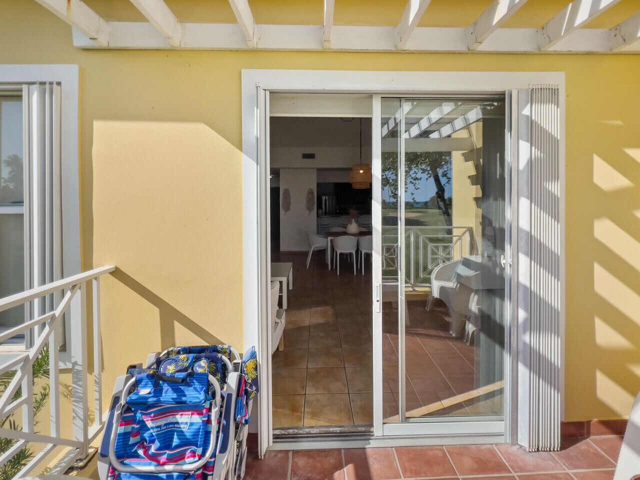 A covered outdoor area with a sliding glass door leading to a patio with a dining table and chairs.