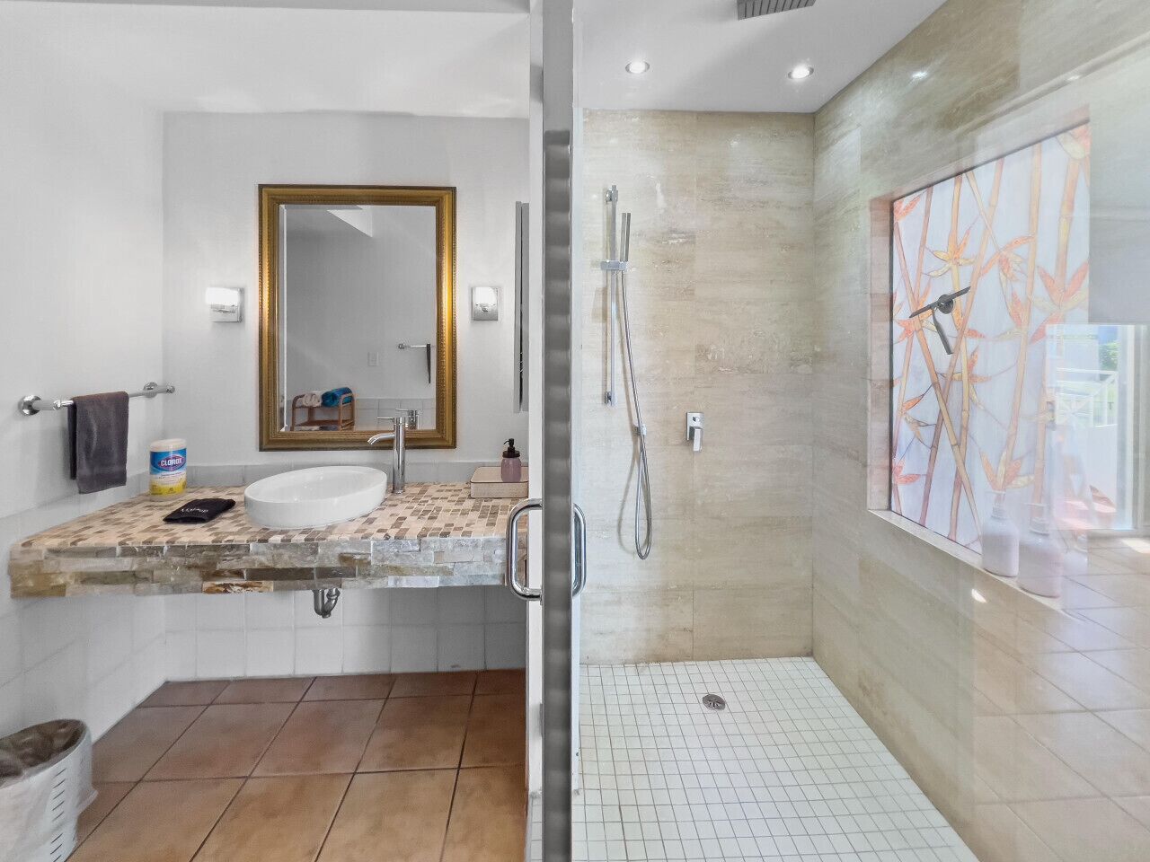 Un bagno moderno con cabina doccia in vetro, uno specchio grande e un pavimento piastrellato.
