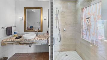 Un bagno moderno con cabina doccia in vetro, uno specchio grande e un pavimento piastrellato.