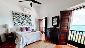 Ein Schlafzimmer mit Bett, Nachttisch, Kommode und Blick auf den Ozean.