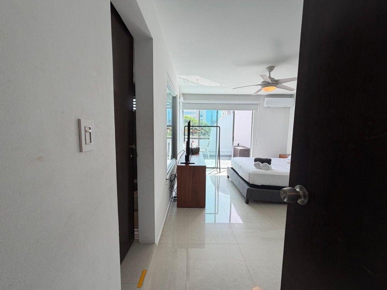 A modern hotel room with a bed, a desk, and a ceiling fan.