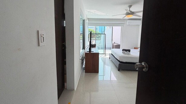 A modern hotel room with a bed, a desk, and a ceiling fan. - Elegant Modern PH W/ Balcony & Parking (San Juan)