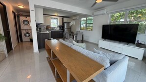 A modern living space with a kitchen, dining area, and a TV. - Elegant Modern PH W/ Balcony & Parking (San Juan)