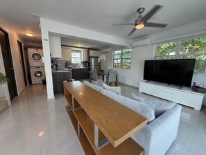 A modern living space with a kitchen, dining area, and a TV. - Elegant Modern PH W/ Balcony & Parking (San Juan)