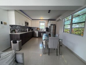 Una cocina moderna con comedor, ventanas amplias y vistas a zonas verdes.