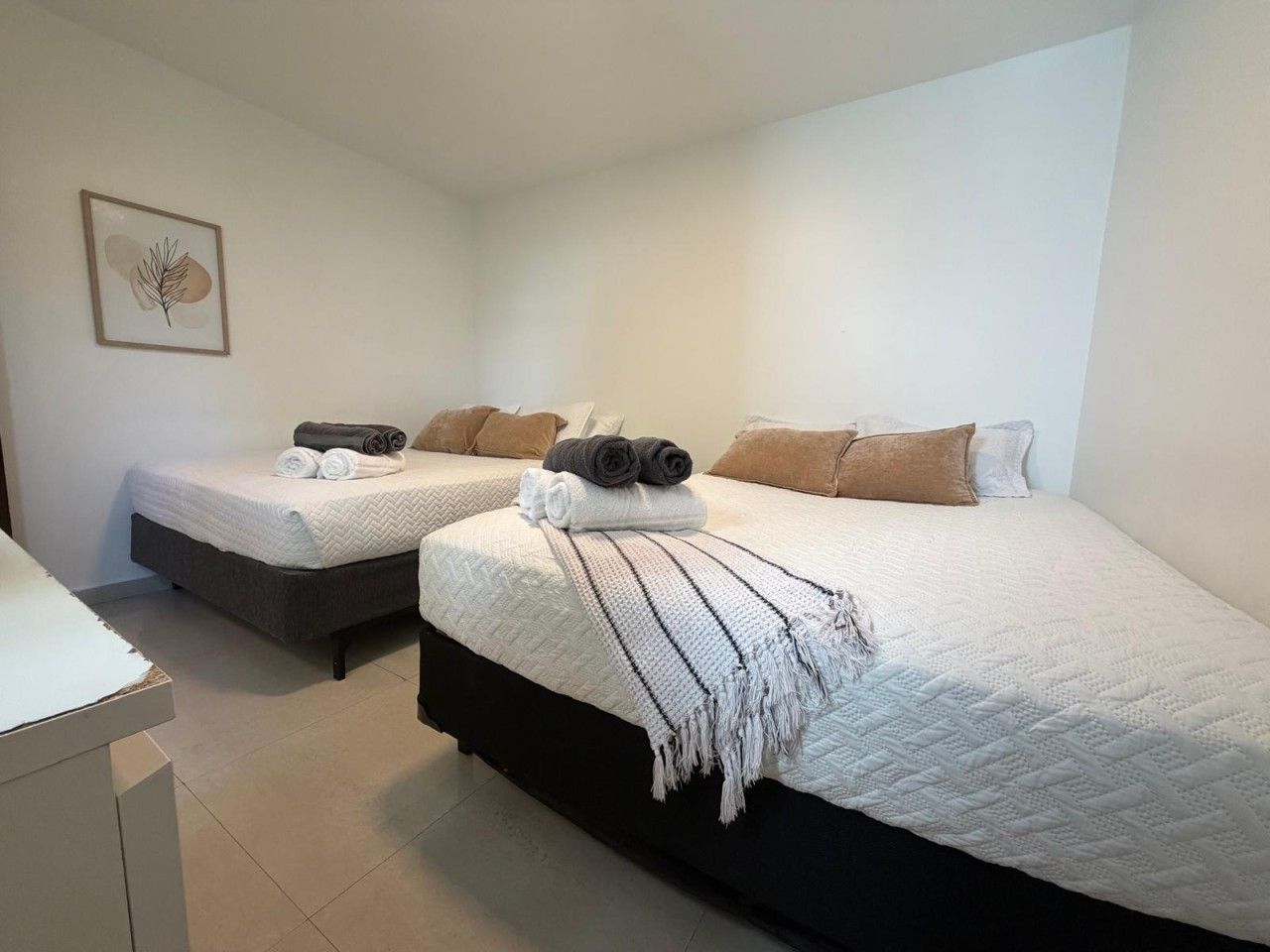 A bedroom with two beds, each with a white quilted bedspread and pillows.