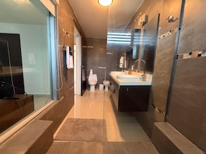 Une salle de bain moderne avec une douche à parois de verre, un meuble-lavabo avec un miroir et des toilettes.