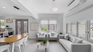 A modern living room with a dining area, grey sofas, a wooden dining table, and a white coffee table. - Spacious and Modern Villa with Pool in Ocean Park (San Juan)